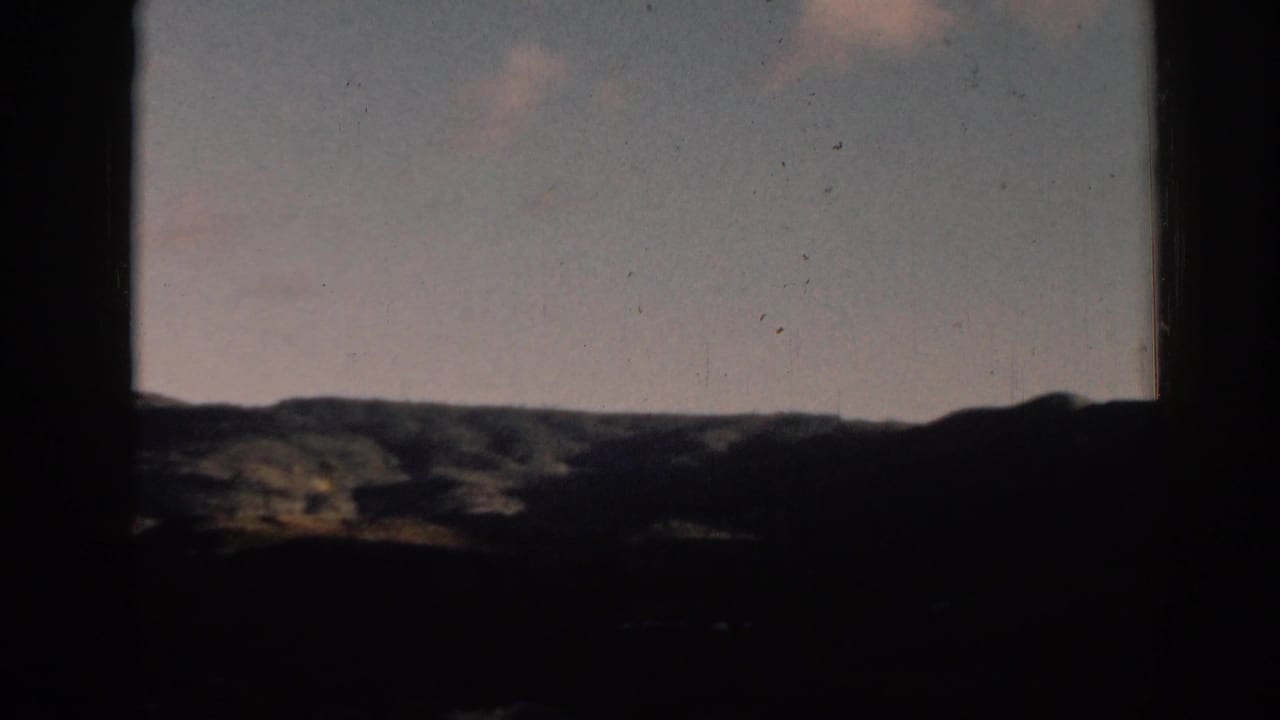 A static 8mm view of rolling hills near Ephesus, with a pale blue sky and dark framing edges.