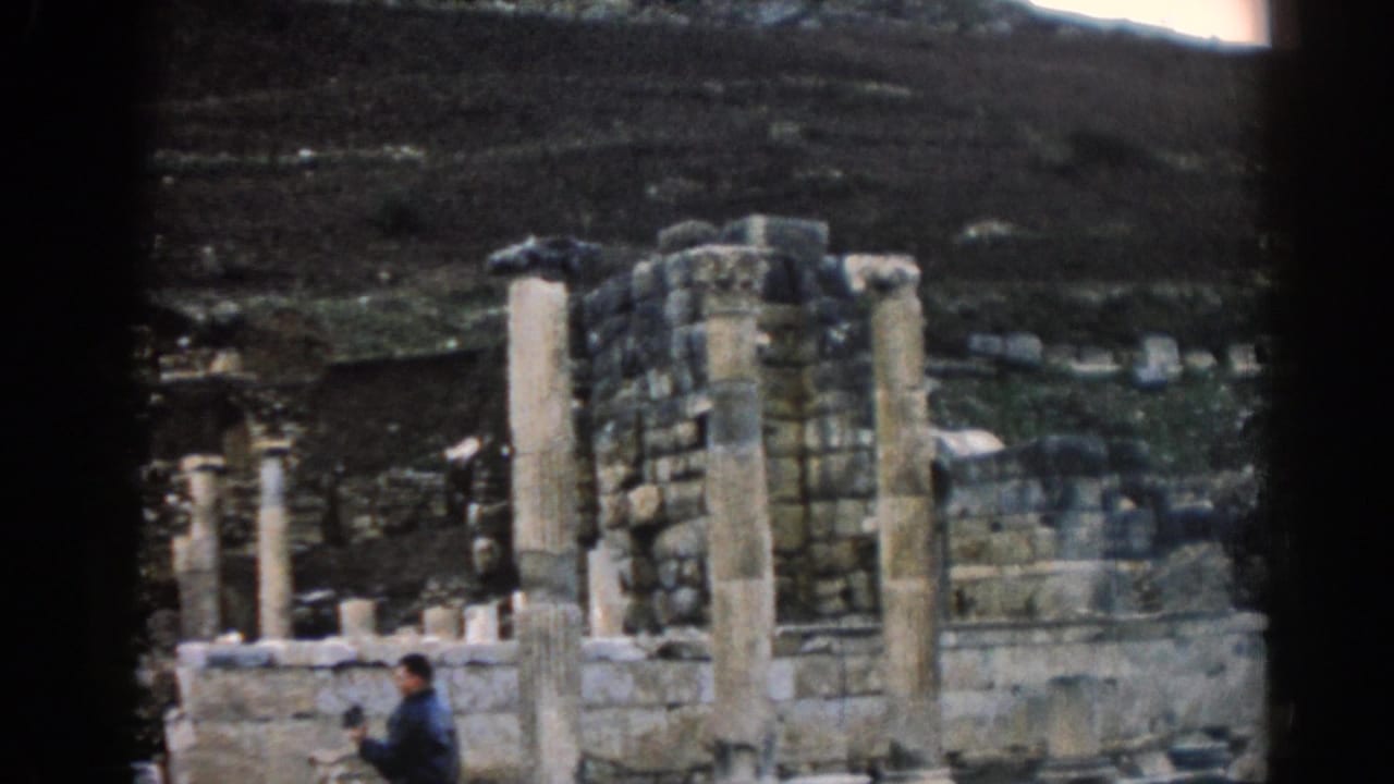 Weathered columns and stone wall fragments with a small visitor visible in the foreground.