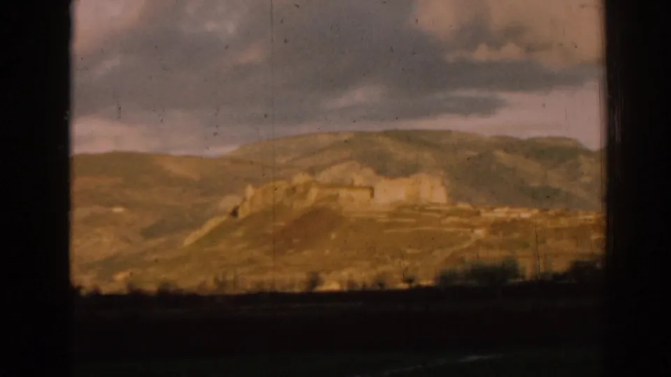 1962 8mm view near Ephesus, Turkey, showing distant ruins on rolling hills through dark vehicle or window framing.