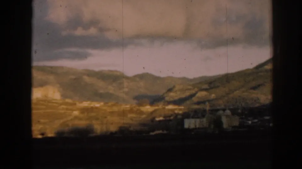 1962 Ephesus-area panorama with rolling hills, scattered white buildings, and dark foreground framing from a moving viewpoint.