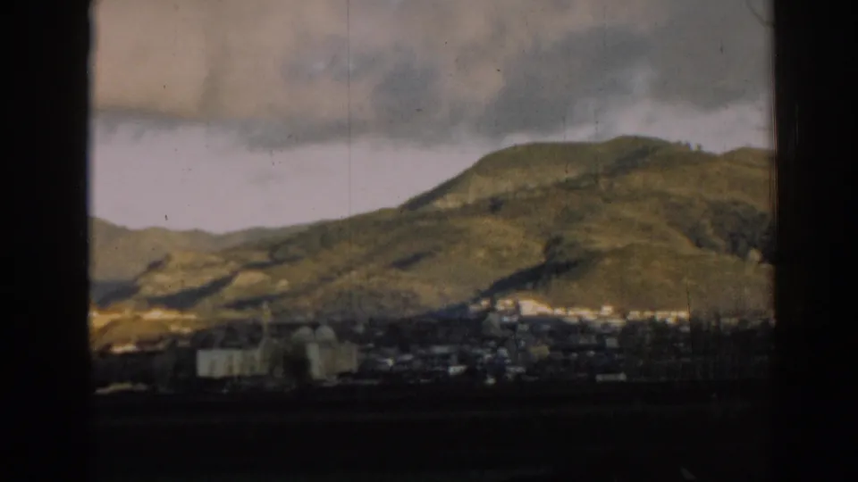 Final frame of the 1962 Ephesus landscape pan, with rolling hills above a distant village and dark 8mm frame edges.