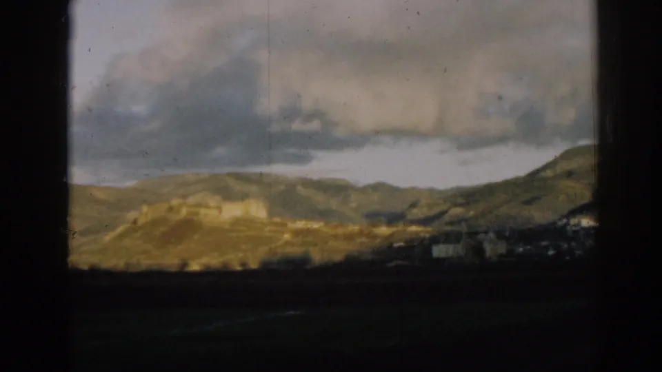 1962 8mm home-movie view near Ephesus, Turkey, showing rolling hills, heavy clouds, and dark foreground land.