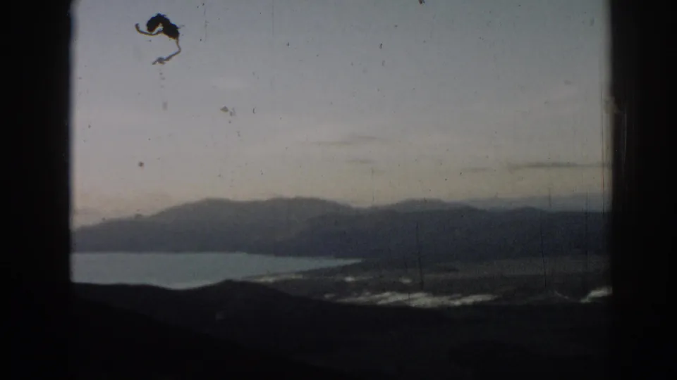 Scenic 1962 Turkey home-movie view of a lake and distant mountains, framed by dark film edges and visible scratches.