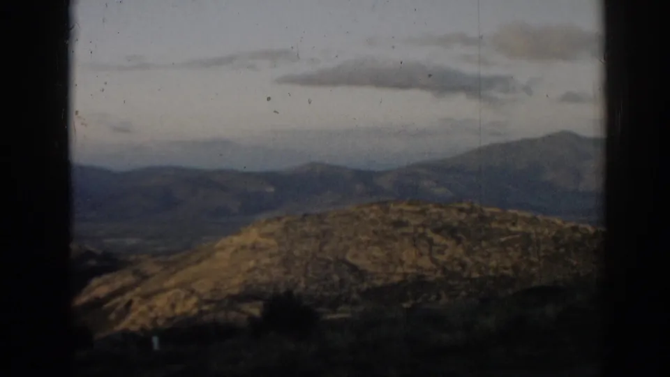 A rocky hillside in the foreground gives way to layered mountains beneath a cloudy sky in 1962 Turkey footage.