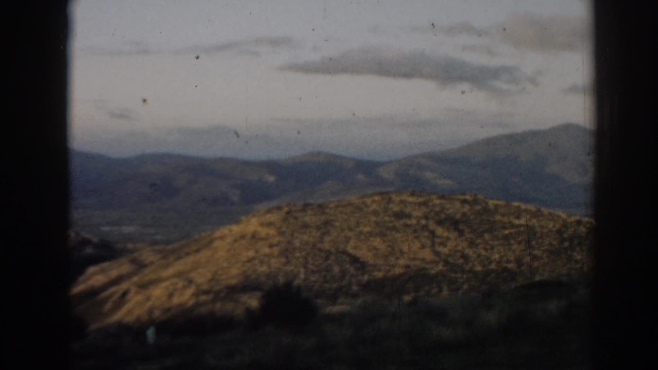 Rolling golden-brown hills and distant mountains seen through dark frame edges.