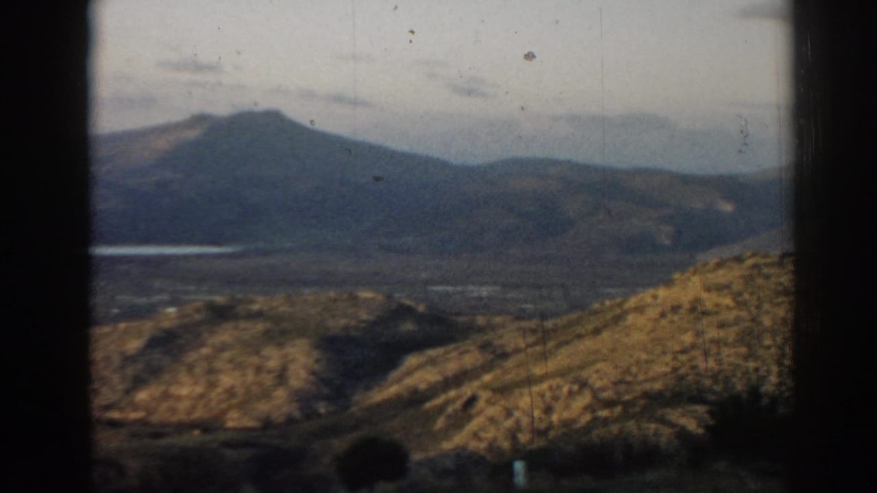 Distant hills and valley seen through dark film-frame borders.