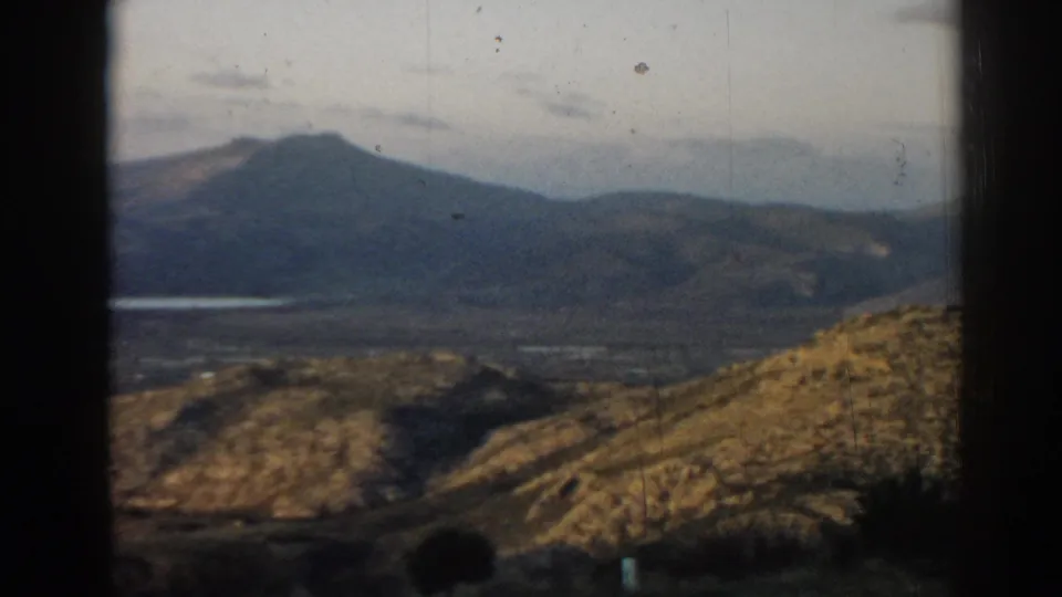 1962 Ephesus-area 8mm frame showing distant hills, a valley, pale sky, and dark borders from the film gate or camera framing.