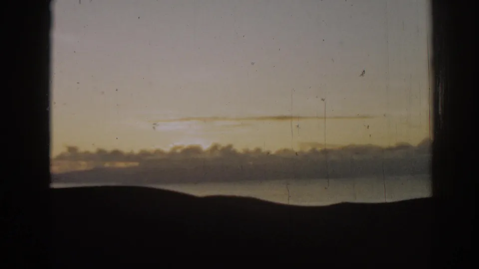 Warm 1962 8mm coastal view near Ephesus, with water, a low silhouetted horizon and fading sky light.