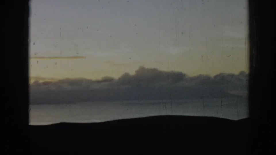 1962 Ephesus, Turkey 8mm frame with muted sky color, low clouds, a dark landform, and a quiet water horizon beneath.