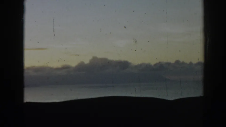 1962 Ephesus, Turkey 8mm closing frame of clouds, silhouetted land, and calm water with visible grain and gate edges.