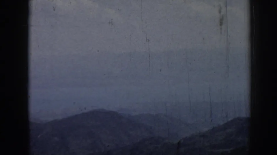 Hazy 1962 Ephesus mountain view with layered ridges, muted sky, visible scratches, and dark 8mm frame edges.