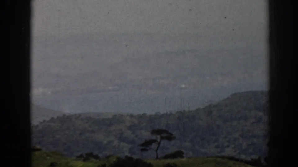 1962 8mm travel view near Ephesus, Turkey, showing hazy hills, water, fields, and a small tree through dark window-like borders.