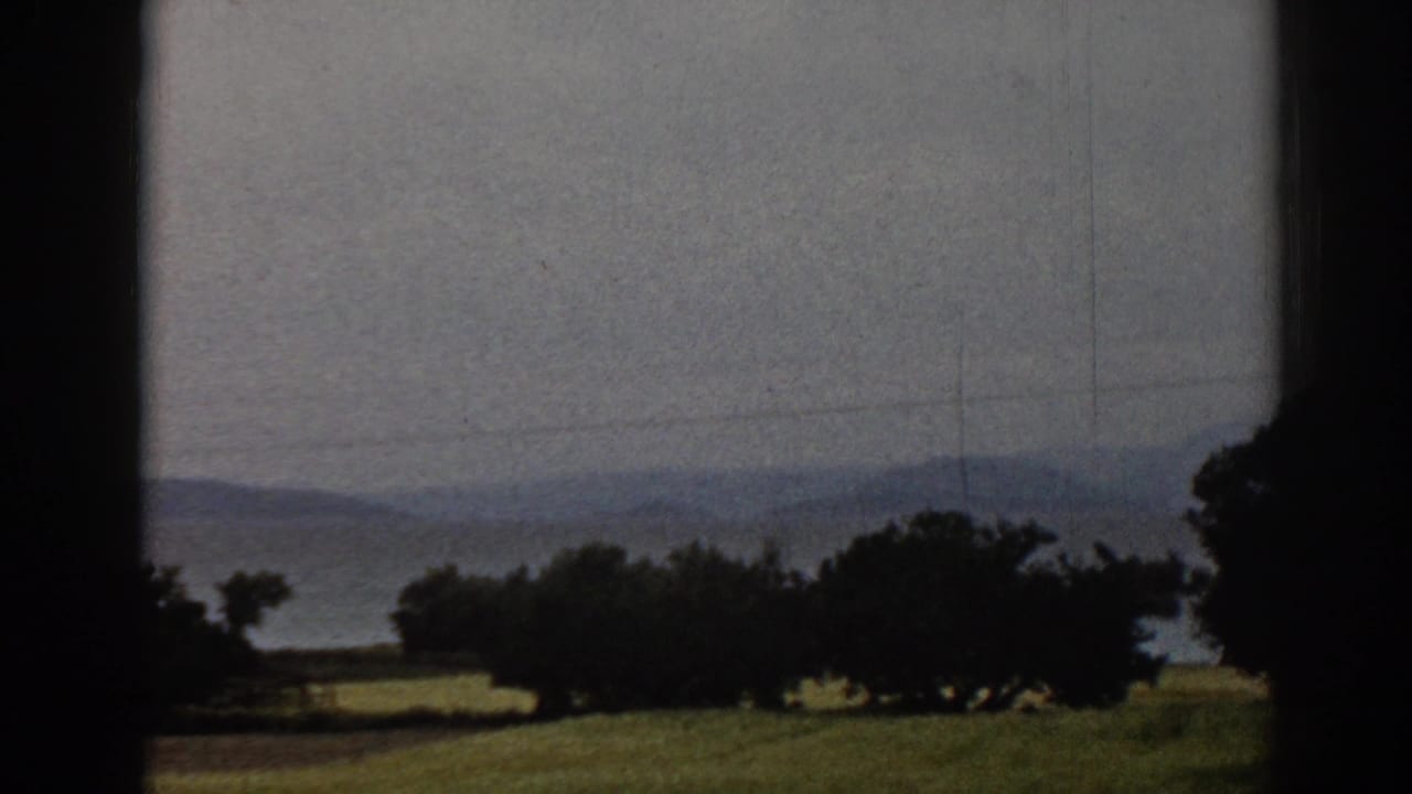 1962 Ephesus countryside view with grass, silhouetted trees, distant hills, power lines, and dark framing from a window or opening.