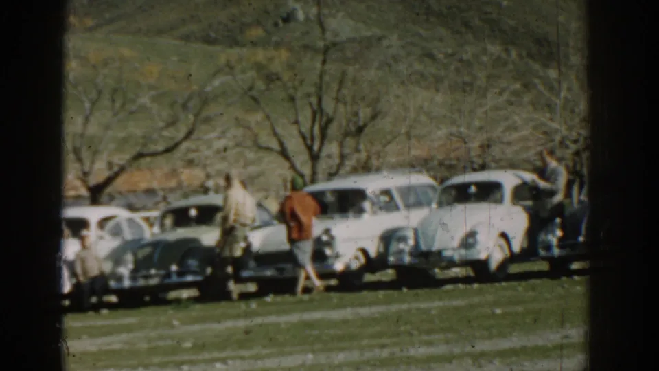 The final frame shows adults beside light and dark classic cars in a rural Izmir setting, with hillside terrain behind them.