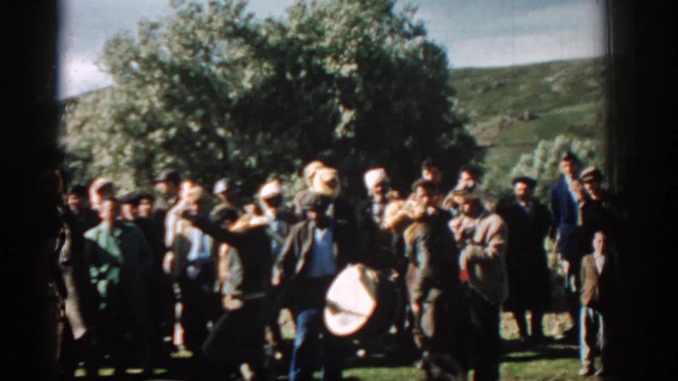 1962 Izmir frame of men gathered outdoors during a celebration, with a large drum visible in the foreground.