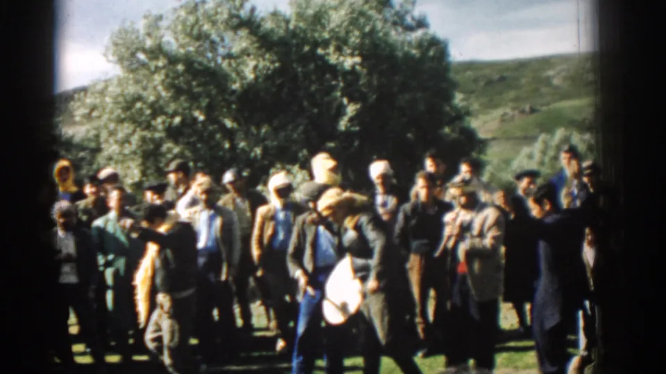 1962 Izmir frame showing a drummer before a gathered crowd in a sunlit field with trees and hillside beyond.