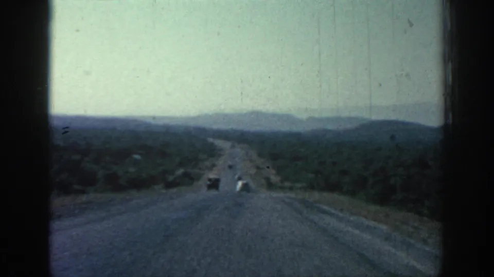 Forward-facing 8mm view of a Rhodes road receding through green hills in 1962.