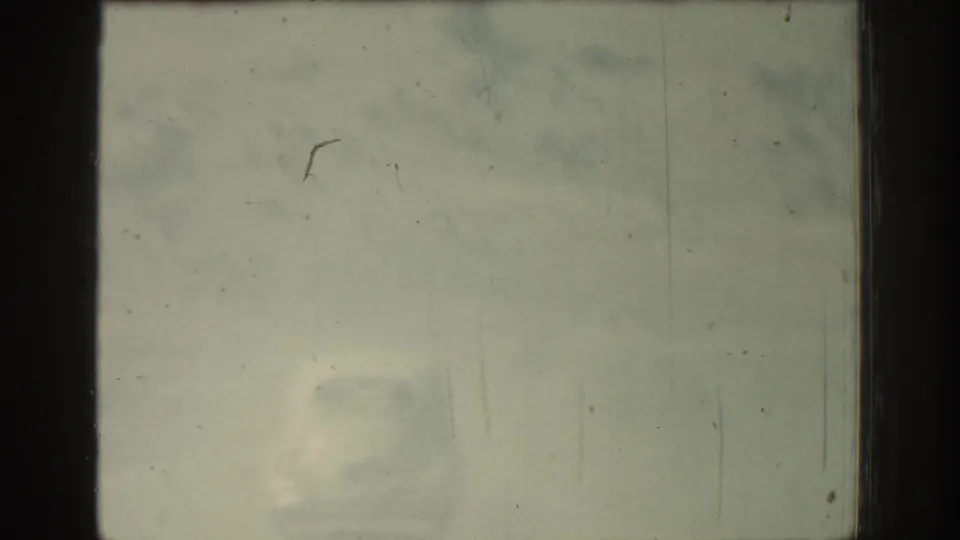 Weathered 8mm frame from the Rhodes travel clip, largely obscured by fading, dust, scratches, and pale exposure.