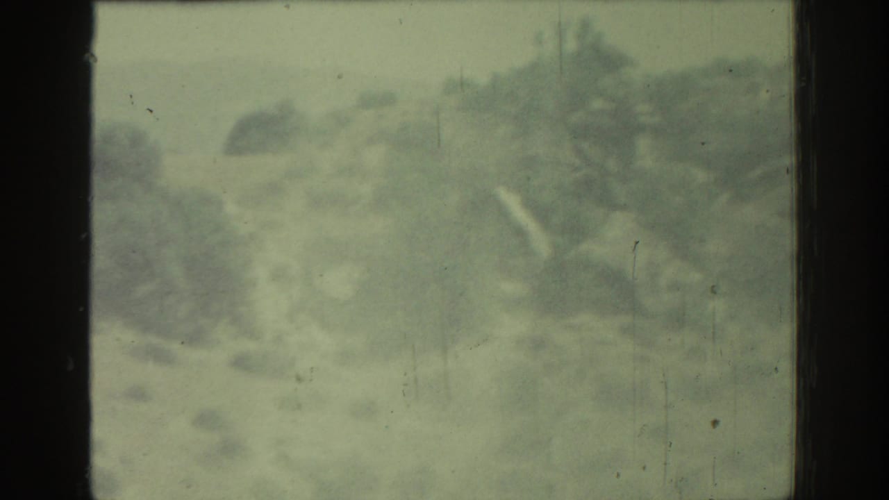 Blurred rocky hillside seen through a dark car window frame.