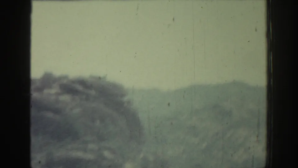 Hazy 8mm passenger view of a low rocky hillside and distant landscape in Rhodes, Greece, from 1962 travel footage.