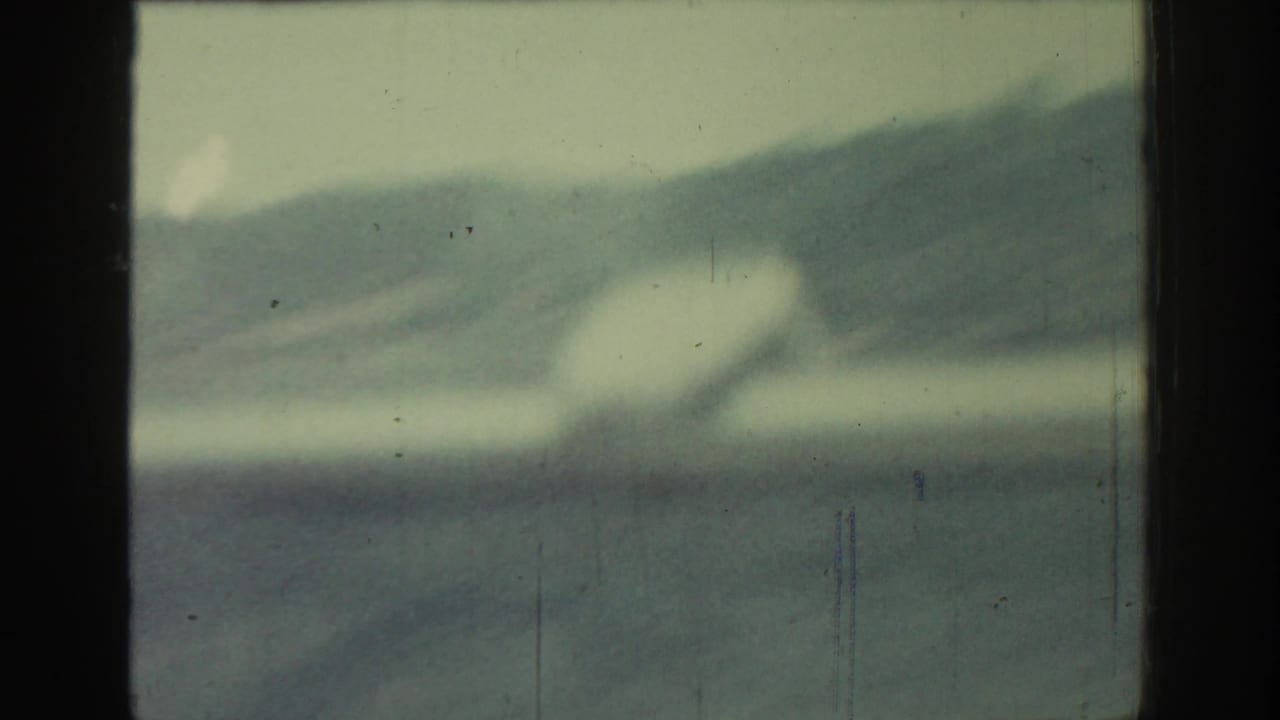 Blurred hills seen through a dark vehicle window frame.
