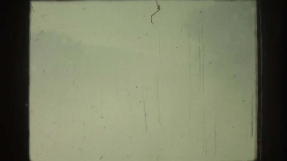 Overexposed 1962 Rhodes 8mm frame with greenish fading, vertical scratches, dust marks, and dark film-edge bands.