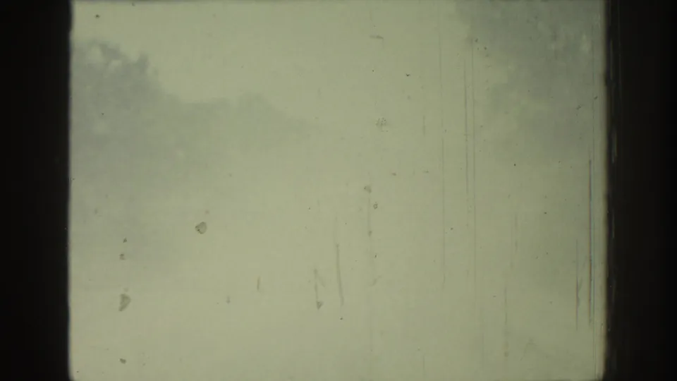 Faded Rhodes 1962 8mm frame showing washed exposure, dark film-frame bars, scattered dust, and faint cloudy density.