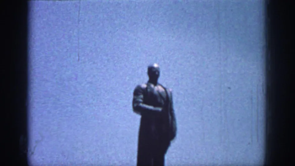 A large standing male statue appears against the sky in a 1962 Rhodes travel shot.