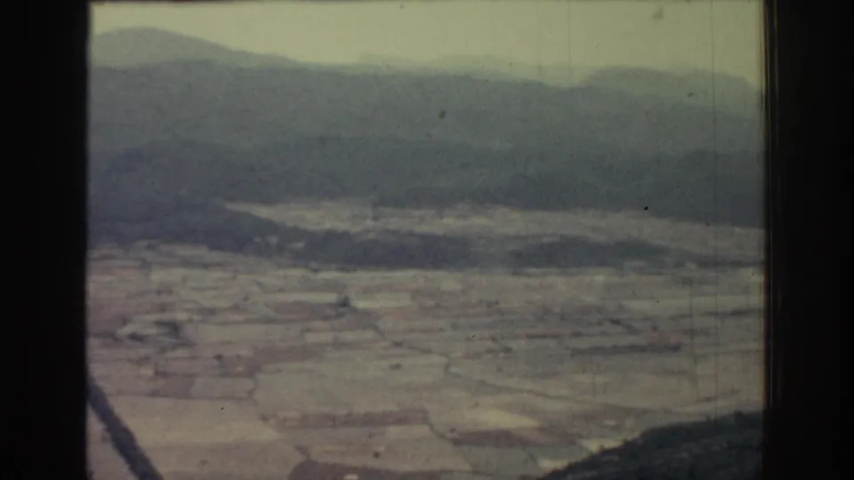 Rhodes, Greece aerial view from 1962 with pale agricultural plots, hazy hills, and a dark divider in the frame.