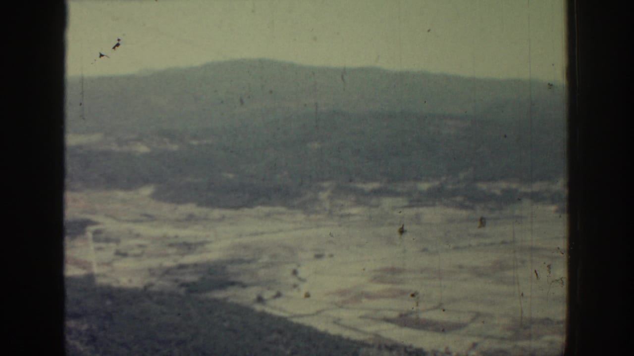 Hazy valley and distant mountains seen from above through an 8mm film frame.