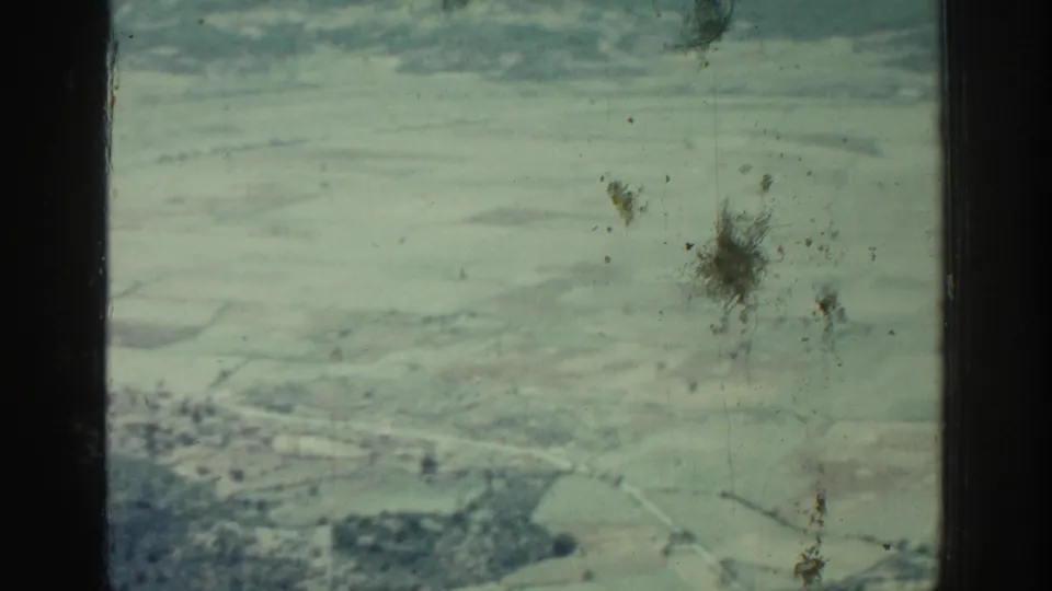 Aerial 8mm view over Rhodes, Greece, with pale fields, winding channels or roads, and dust on the film surface.