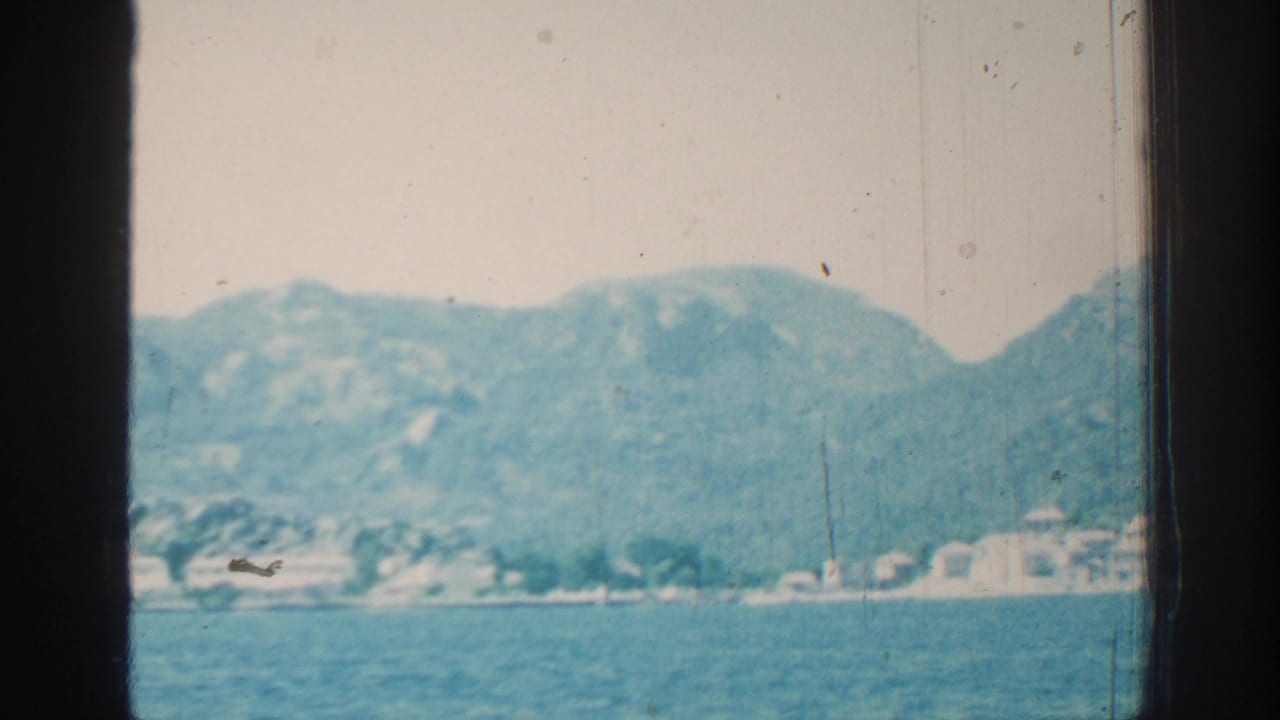 Coastal hills and sea seen through dark vessel window frames.