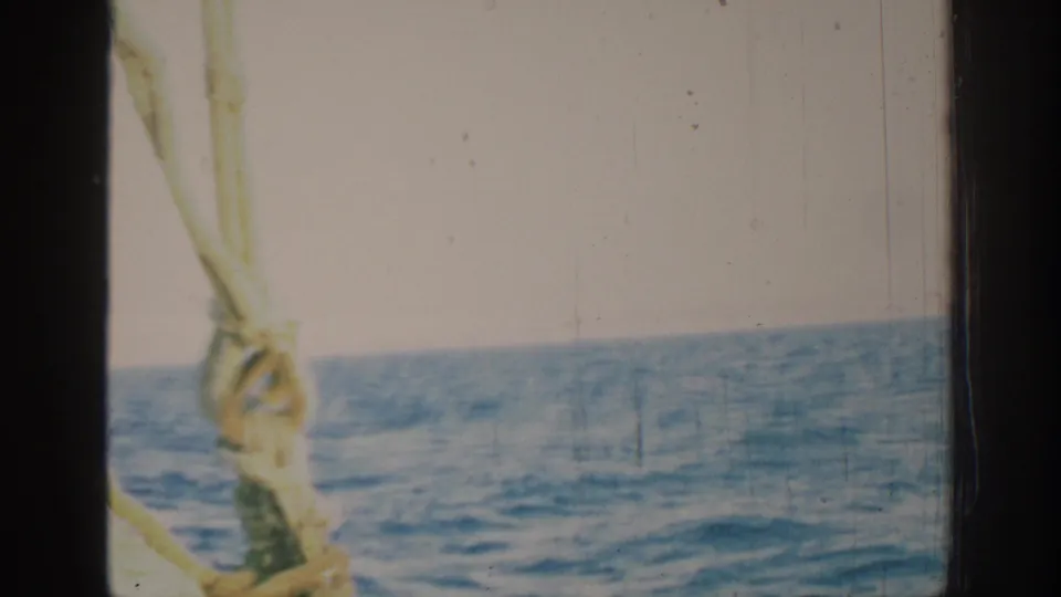 1962 8mm sailing view near Rhodes, Greece, with blue water, pale sky, and a rope knot crossing the foreground.