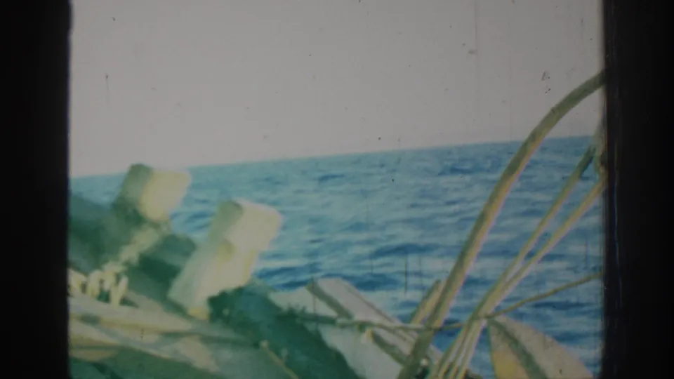 1962 Rhodes, Greece 8mm frame looking across sailboat deck fittings and curved rigging toward blue ocean waves.