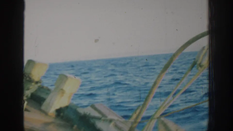 1962 Rhodes, Greece 8mm frame showing sailboat deck hardware and rigging in the foreground with rolling blue sea behind.