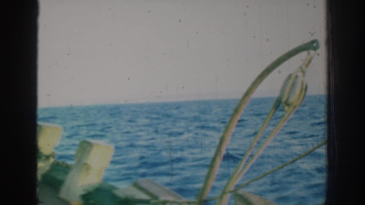1962 Rhodes, Greece 8mm view of open blue sea through a boat-side frame with railings and weathered fittings in the foreground.