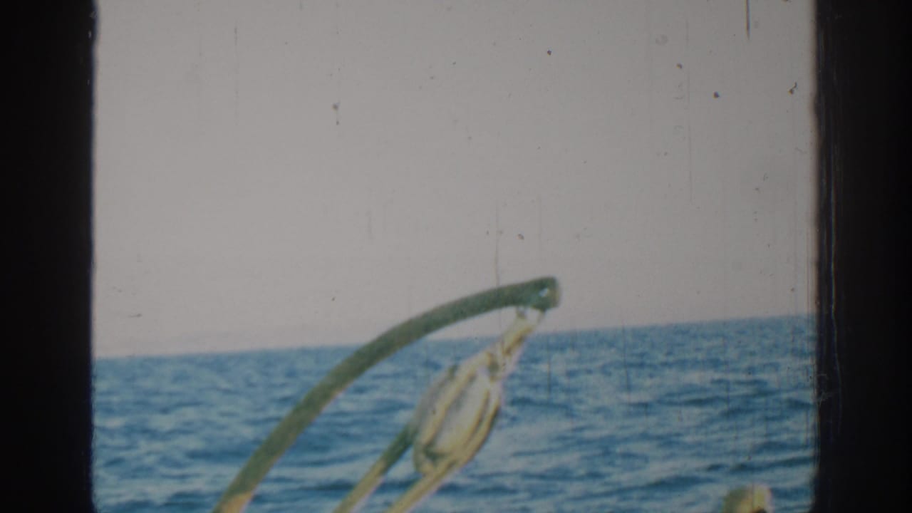 1962 Rhodes, Greece home-movie frame showing open sea, horizon, pale sky, and curved boat hardware through visible film borders.