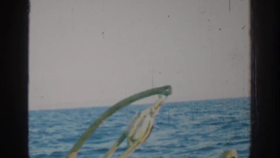 1962 Rhodes, Greece home-movie frame showing open sea, horizon, pale sky, and curved boat hardware through visible film borders.