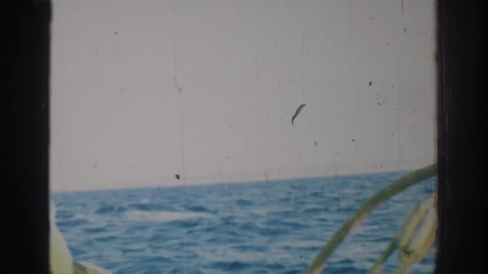 1962 Rhodes, Greece home-movie still showing open blue water, a tilted horizon, and partial boat hardware near the lower frame.