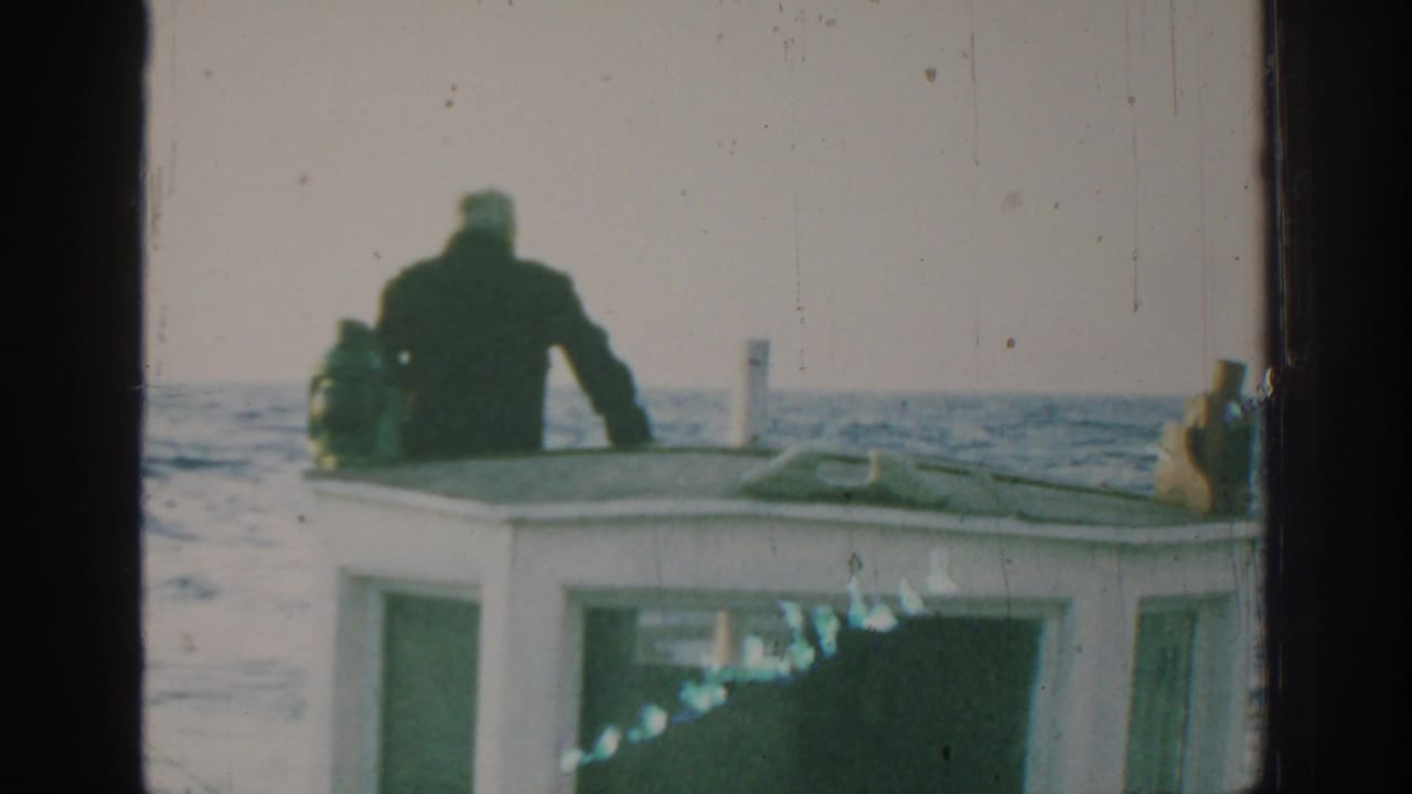 Small cabin boat at sea with a man standing near the bow.