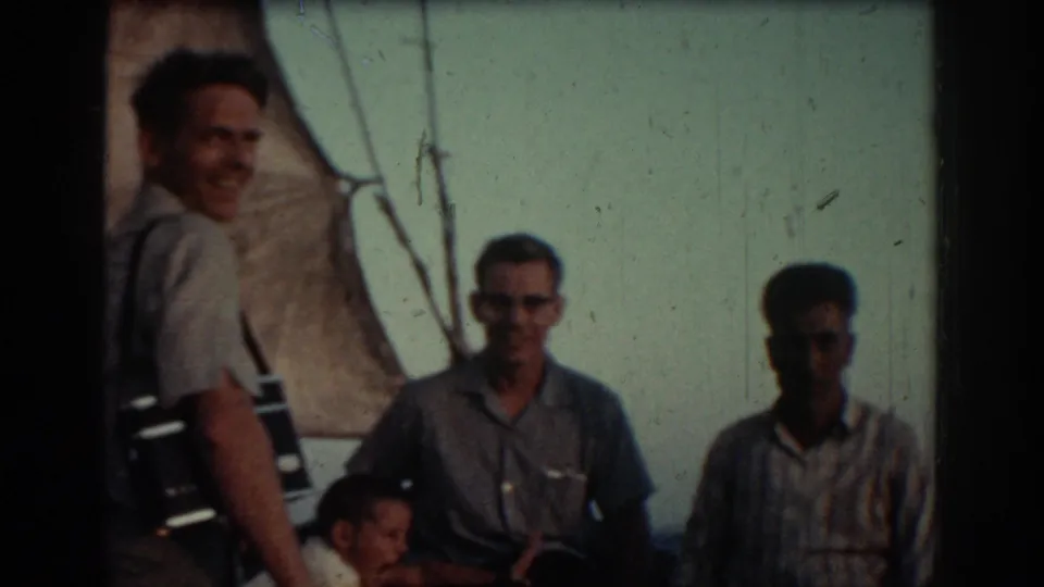 The final frame shows several adults near rigging on the boat, with faded color and dark exposure from the 8mm scan.