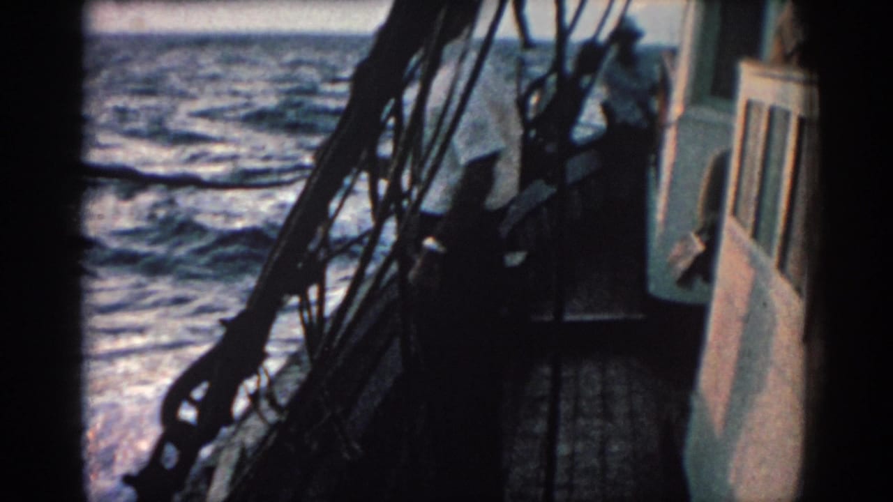 Boat deck and cabin edge with rigging silhouetted against choppy sea water.