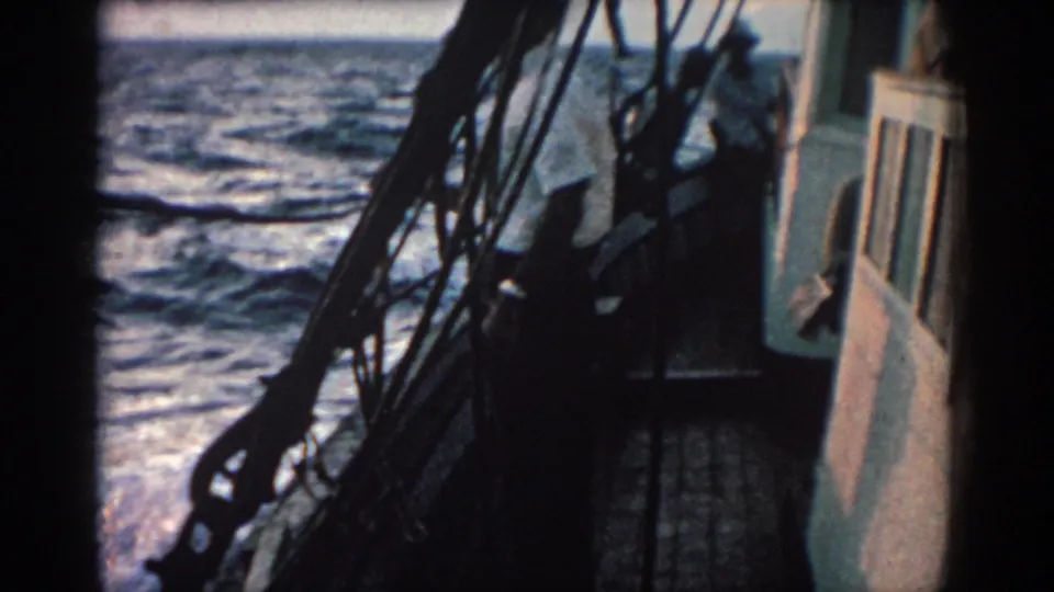 The boat deck, cabin side, and dark rigging appear against moving sea in the 1962 Rhodes, Greece home-movie footage.