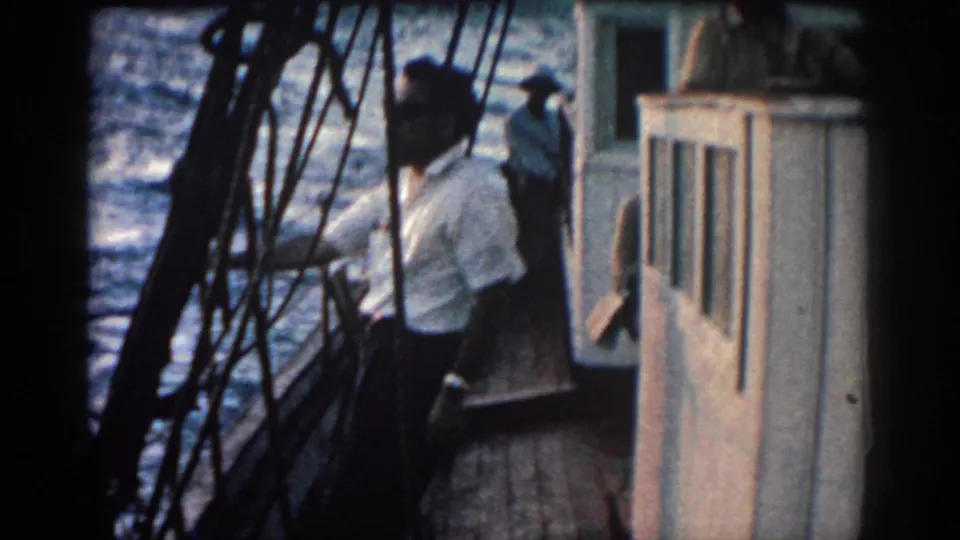 The man stands close to the rail and cabin on a small boat, with Rhodes, Greece travel context supported by the clip metadata.