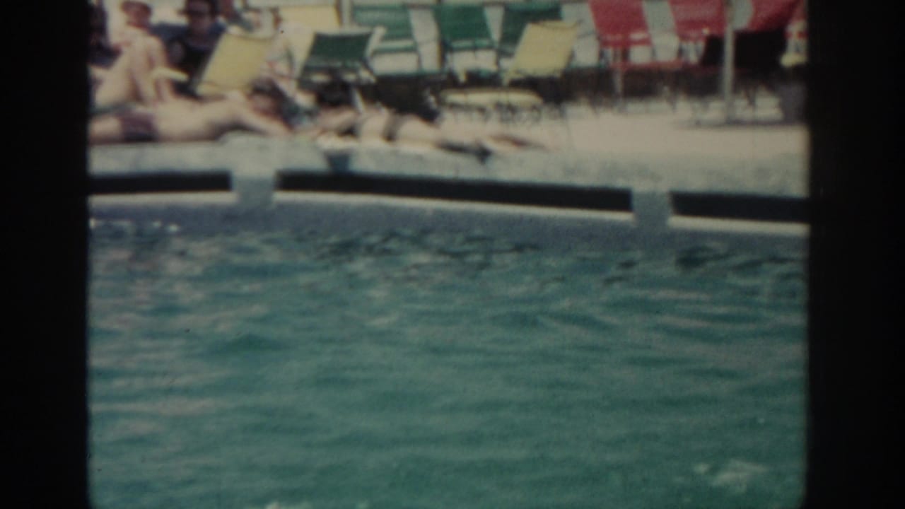 1962 Rhodes poolside view showing turquoise water, reclining adults, and rows of colorful resort lounge chairs.