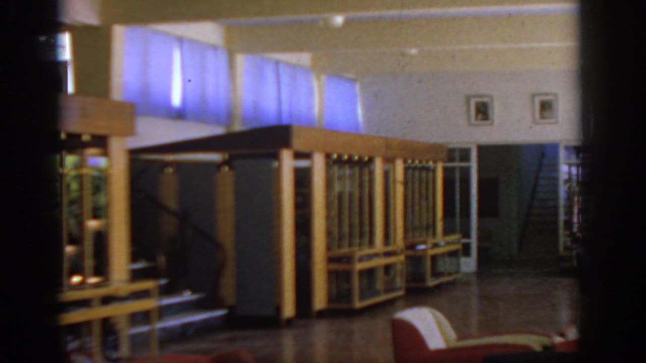 Hotel lobby with wood display cases, blue curtains, stairway, and polished floor.