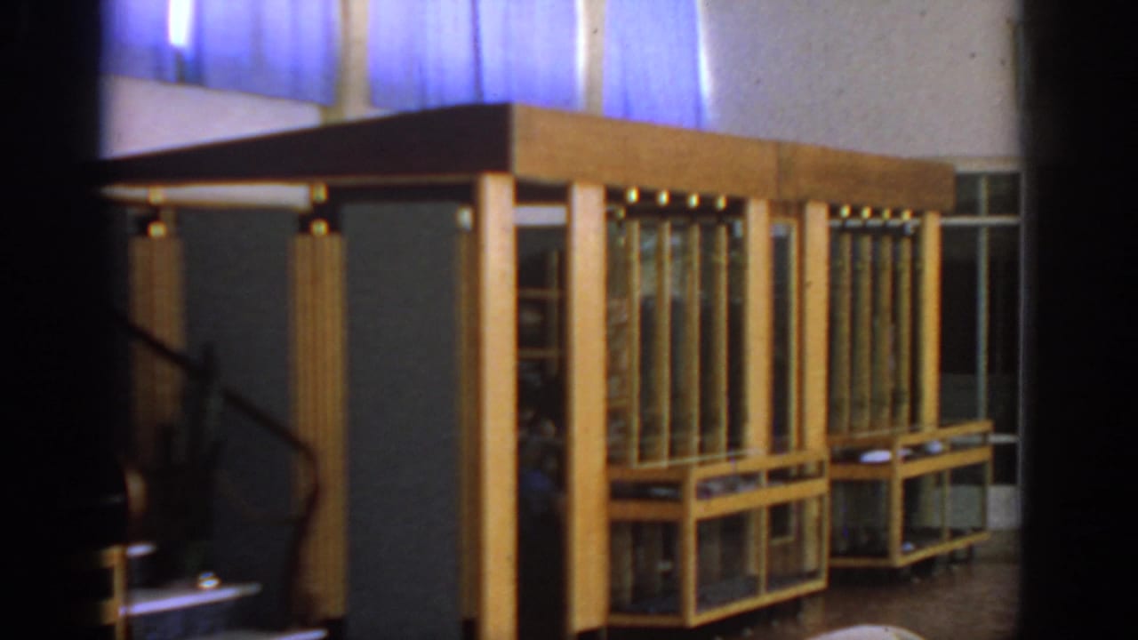 Closer lobby view with glass display counters, wood paneling, blue curtains, and stair rail.