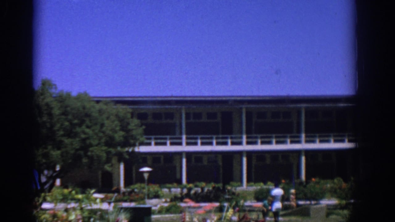 Two-story building and planted garden with small people visible near the lower right.
