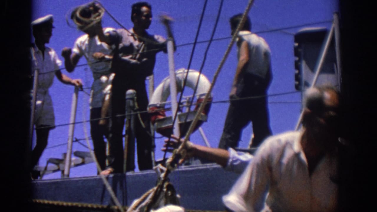 1962 Rhodes, Greece frame with sailors and crew handling deck equipment beside rigging and a life preserver.