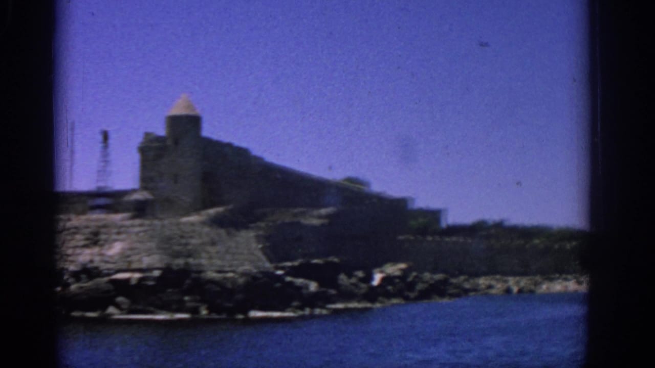 Fortress tower and long stone wall seen from across the water.